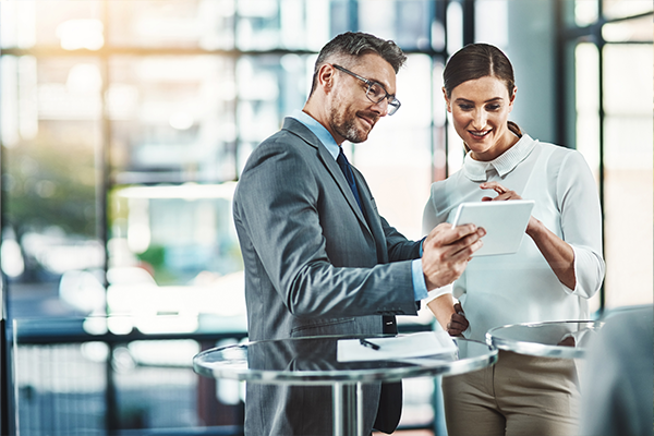 Dwie osoby omawiające dokumenty przy biurku w kontekście usług związanych z fotowoltaiką