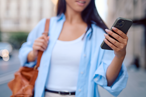 Kobieta idąca ulicą sprawdza powiadomienie na telefonie