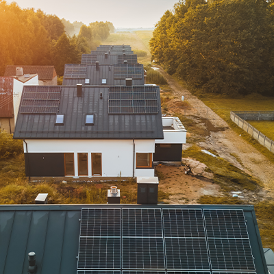 Szereg nowoczesnych domów jednorodzinnych z instalacjami fotowoltaicznymi widziany z lotu ptaka.