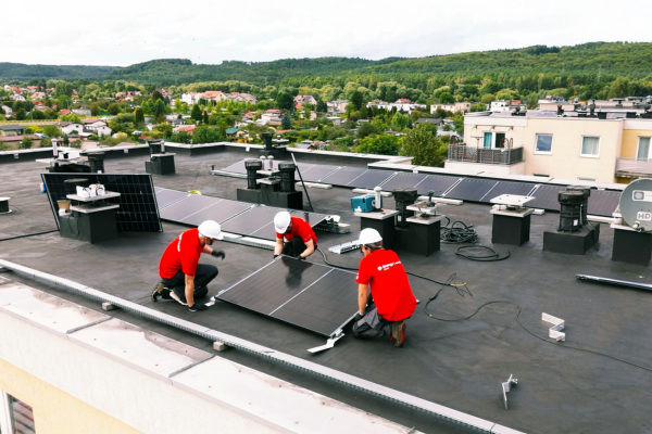 Pracownicy Energi Obrotu montujący instalację fotowoltaiczną na dachu budynku.